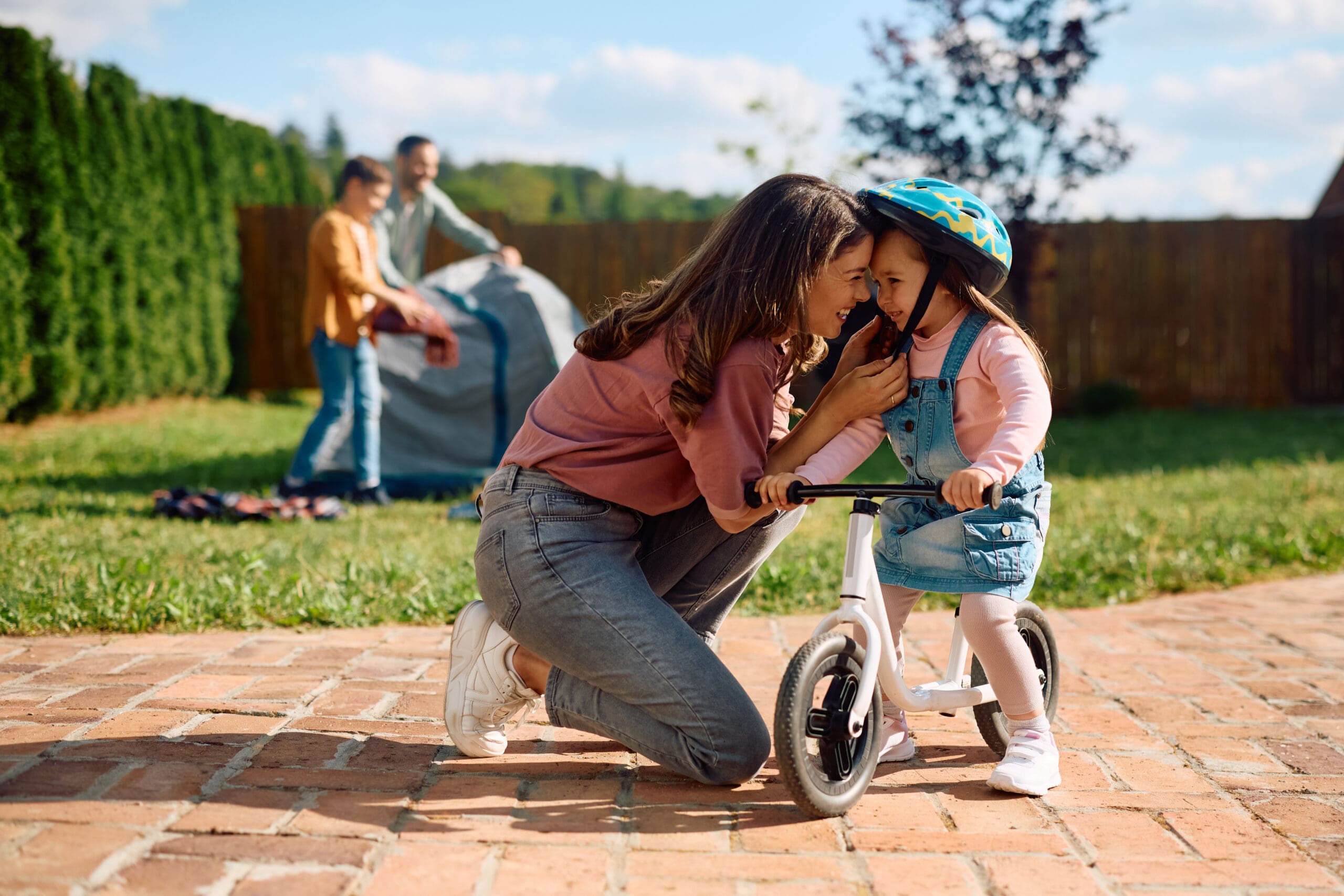 Loving mother adjusting daughter bicycle helmet before the ride.